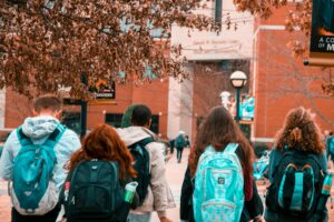 Group of kids shown from the back walking into college building.